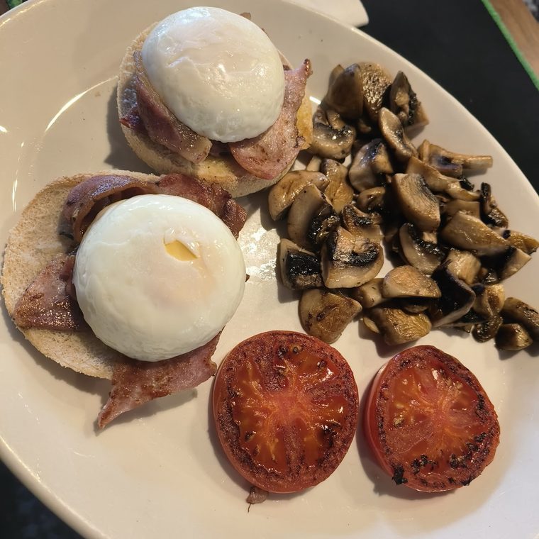 Poached eggs on bacon and muffins with mushrooms and grilled tomatoes